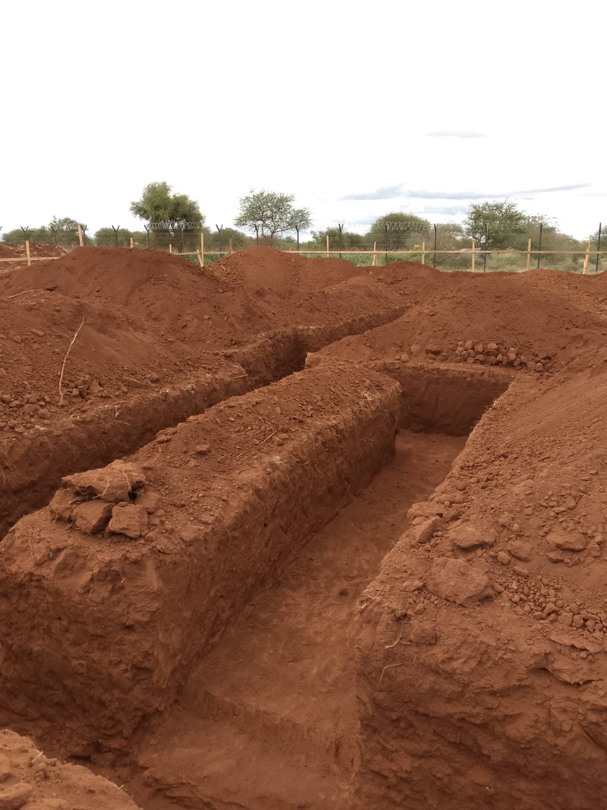 Deep foundation trench cut into red soil